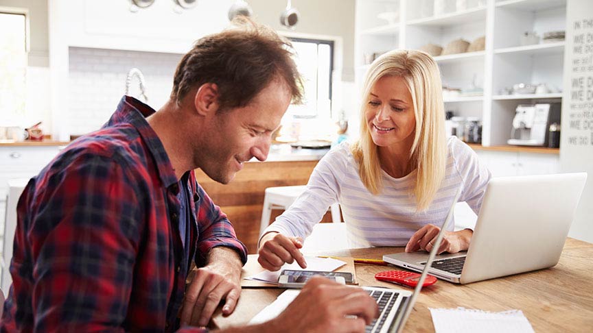 man and woman sitting in front of open laptops pointing at smartphones on the table